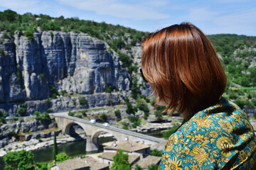 Woman enjoying a breathtaking view of the river and old stone bridge at Balazuc village. France