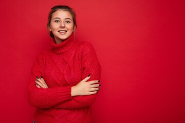Fototapeta premium Young smiling beautiful brunette woman with sincere emotions isolated on background wall with copy space wearing casual red sweater. Positive concept