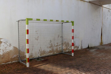 Old football goal against the background of a peeling wall