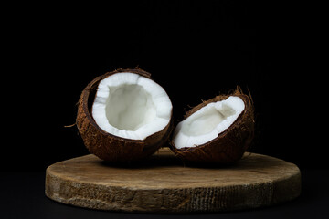 Isolated coconut on a black background. Two halves of a coconut on a dark background. Healthy fruit