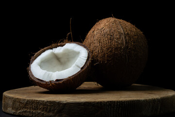 Isolated coconut on a black background. Half a coconut and a whole coconut on a dark background. Healthy fruit