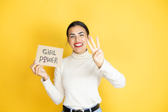 Young beautiful activist woman protesting holding poster with girl power message showing and pointing up with fingers number three while smiling confident and happy
