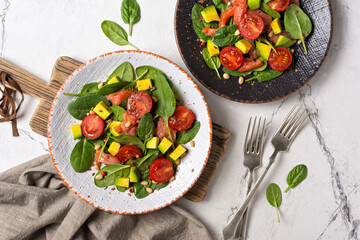 Healthy salad with fresh baby spinach, cherry tomatoes, avocado and salmon fish
