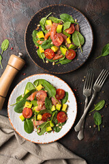 Healthy salad with fresh baby spinach, cherry tomatoes, avocado and salmon fish