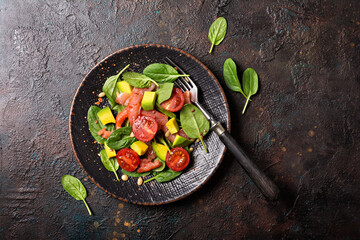 Healthy salad with fresh baby spinach, cherry tomatoes, avocado and salmon fish