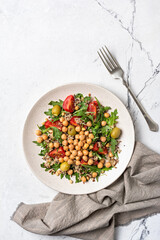 Healthy vegetarian salad with cooked chickpeas, chia seeds, fresh arugula, cherry tomatoes and olives