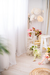 Flower arrangement. A large mirror in a beautiful frame, draped with tulle, the reflection of beautiful vases with bouquets of flowers, in a bright interior, a festive decoration with gift hat boxes.