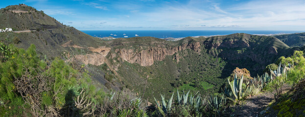 Panoramic view of volcanic landscape of Caldera de Bandama crater and Pico de Bandama with circular hiking trail. Gran Canaria, Spain. Sunny day, blue sky. © Kristyna