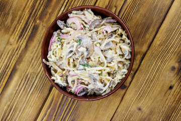Tasty salad of grated celery root, mushrooms, onions on wooden table. Top view