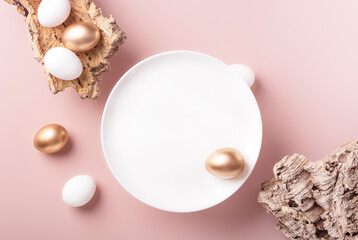 White and gold Easter eggs lie on the bark of a tree, on a white plate on a powdery background, horizontal orientation, copy space