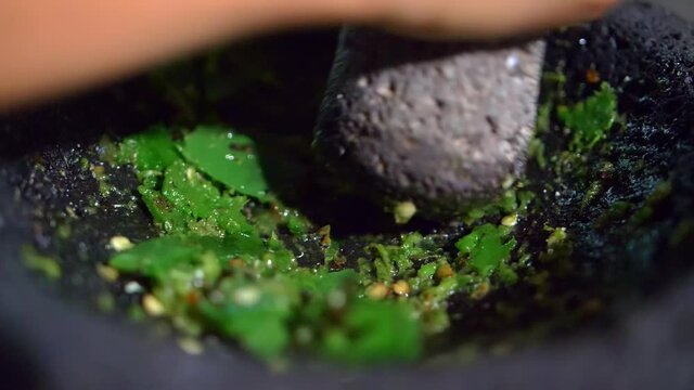 Close-up of hand grinding peppers in a Mexican molcajete
