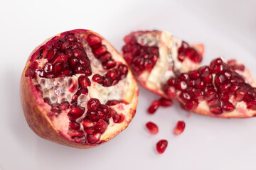 Fresh ripe sliced pomegranate fruit with red seeds isolated on white background