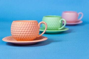 It's coffee time. blue,orange and green  coffee cups on the table.blue  background.