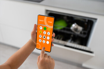 little girl holds a smartphone and operates a dishwasher, smart home