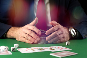 Businessman at green gaming table with game chips, cards and dice playing poker and blackjack in casino