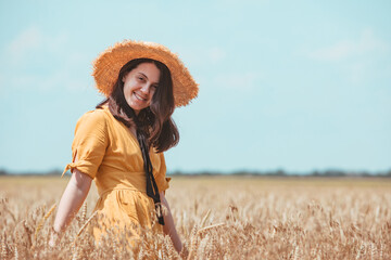Naklejka na ściany i meble woman in yellow sundress walking by wheat field