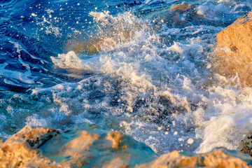 Waves crushing on the rocks on beach in the morning time. Sunrise on the wavy sea with rocks