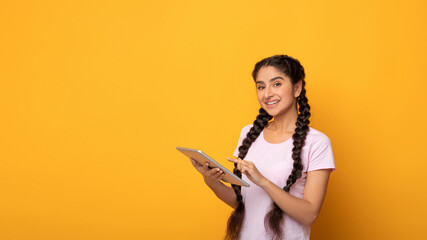 Confident young indian lady holding and using digital tablet