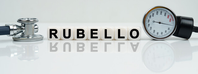 On a reflective white surface lies a stethoscope and cubes with the inscription - RUBELLA