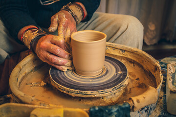 The master forms a clay cup on a potter's wheel. A potter's hands preparing a clay pot. Close-up.