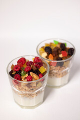 muesli dessert with yogurt and candied or dried fruits with raspberries on top in glass isolated on white background. Granola breakfast