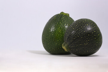 A couple of round zucchini on white background with copy space
