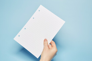 Template for text message: Hand holding the notebook bland lined paper sheet with the copy text space on the bright solid blue fond background