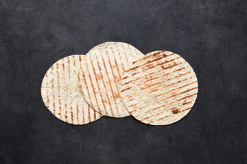 Grilled tortilla. Mexican flatbread - tortilla on a black concrete background.