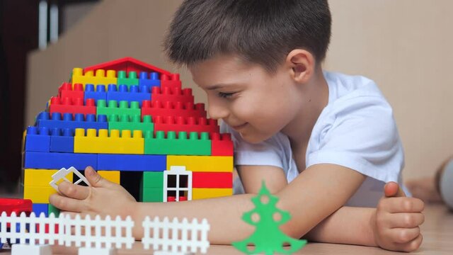Little boy playing with lots of colorful plastic blocks constructor indoor, building house