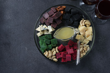 Multicolored gourmet cheese, olives, nuts, honey and sliced lemon on dark background. Appetizer for a wine party. Top view