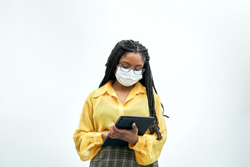 Portrait of a smiling businesswoman in the office using a tablet. She wears a face mask because of the coronavirus pandemic.