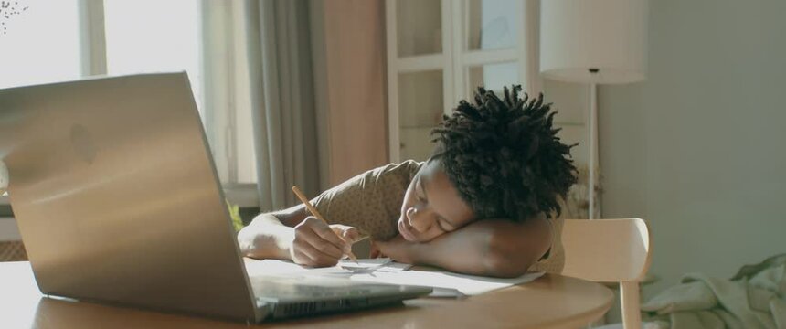 African American Black kid boy doing his homework or having a video call with class and teacher. Distance learning from home during isolation. Shot with 2x anamorphic lens
