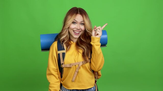 Teenager woman with mountaineering backpack intending to realizes the solution while lifting a finger up over isolated background chroma key