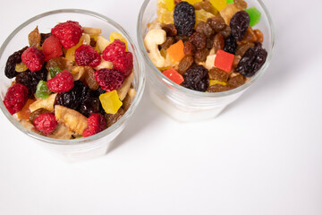muesli dessert with yogurt and candied or dried fruits with raspberries on top in glass isolated on white background. Granola breakfast