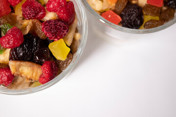 muesli dessert with yogurt and candied or dried fruits with raspberries on top in glass isolated on white background. Granola breakfast