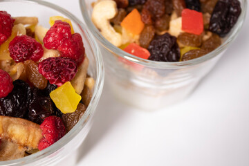 muesli dessert with yogurt and candied or dried fruits with raspberries on top in glass isolated on white background. Granola breakfast