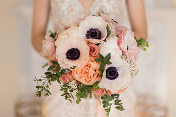 Elegant wedding bouquet in pastel peach colors: ranunculus, peony roses and eucalyptus.  