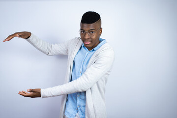 Young handsome african american man wearing casual clothes gesturing with hands showing big and large size sign, measure symbol. Smiling . Measuring concept.