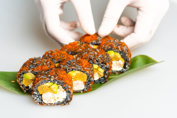 Cook hands making japanese sushi roll. Japanese chef at work preparing delicious sushi roll with eel and avocado. Appetizing japanese food.
