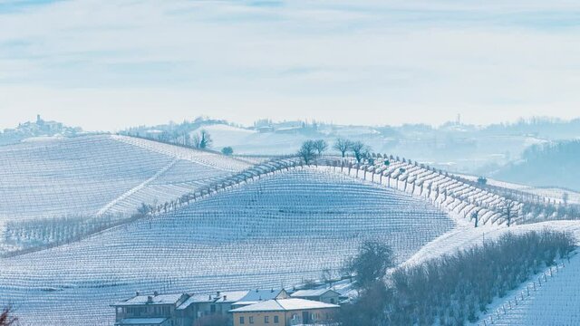 Pan: Italy Piedmont row of wine yards, unique landscape in winter with snow, rural village on hill top, italian historical heritage nebbiolo grape agriculture panoramic view