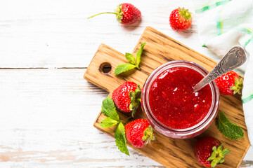 Strawberry jam in the glass jar with fresh berries at white. Top view with copy space