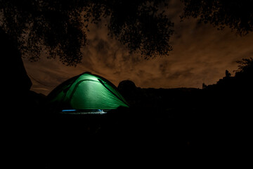 beautiful view of green tourist tent at night with light inside it