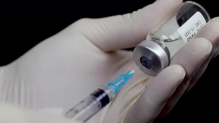 Manos en guantes llenando jeringuilla para inyección de vacuna