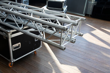 Stack of metal trusses for mounting the stage.  A metal truss lies on a box. Сonstruction stage.