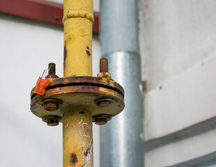 A yellow gas pipe with a coupler runs along the facade of a multi-story building. The house is...
