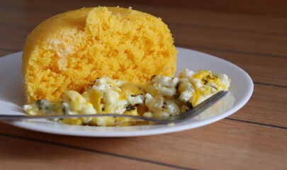 Brazilian couscous and scrambled eggs (Cuscuz com ovo) on wooden background. Typical Couscous of Northeast of Brazil.