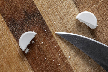 Tablet Sliced in half and knife on a wooden cutting board.
