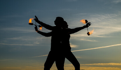 Ignite your dancing flame. Dancing couple spin burning poi. Flame dancers on idyllic sky. Evening...
