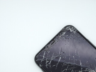 Modern space grey smartphone with a broken glass display and damaged curved body close-up isolated on white background