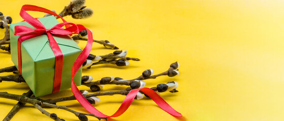 Gift boxes with red ribbons. Willow branches on a yellow background.